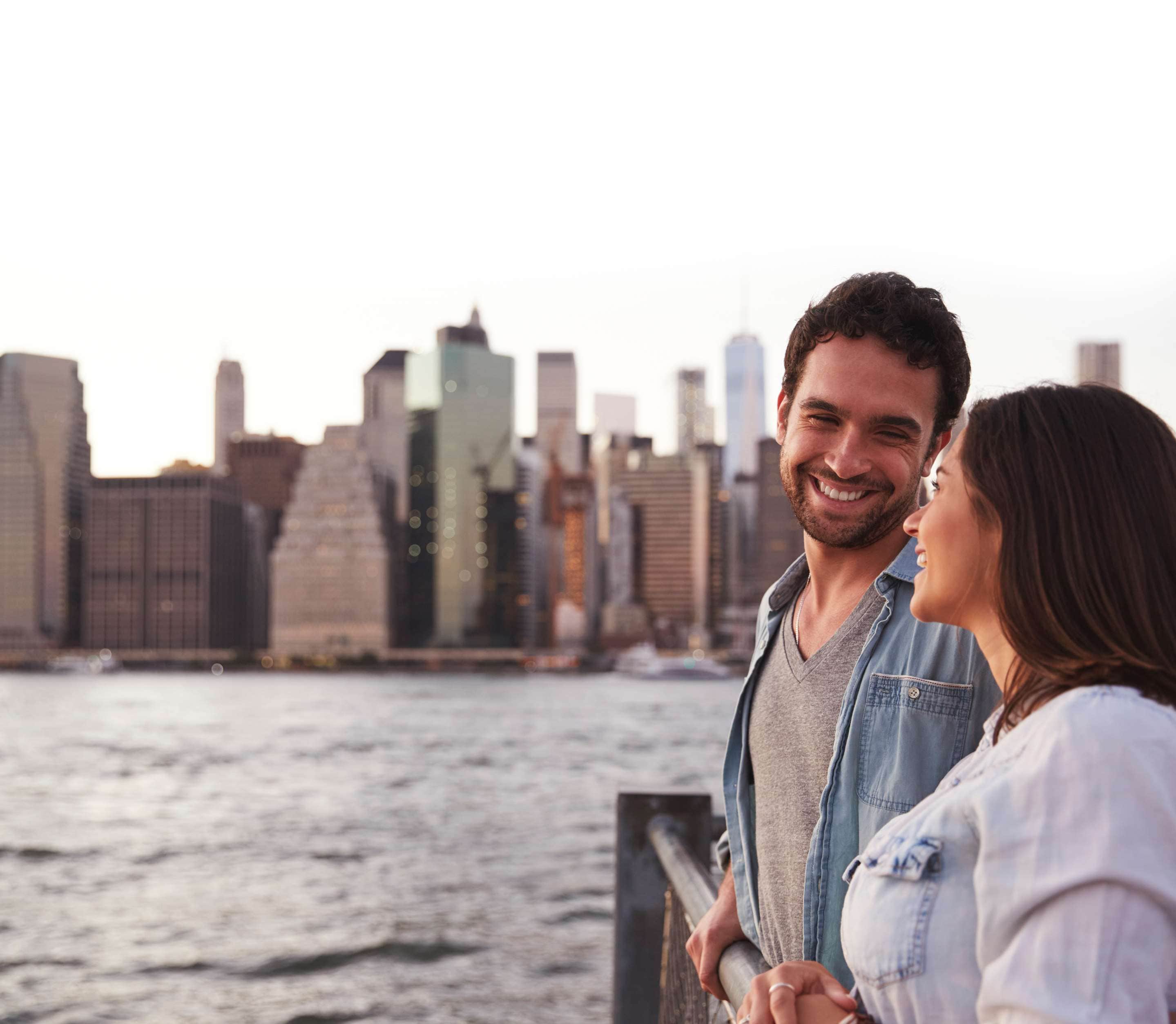 A couple overlooking a bay with a cityscape in the background